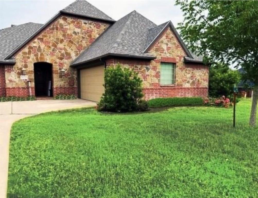 a view of a house with brick walls and a yard with plants