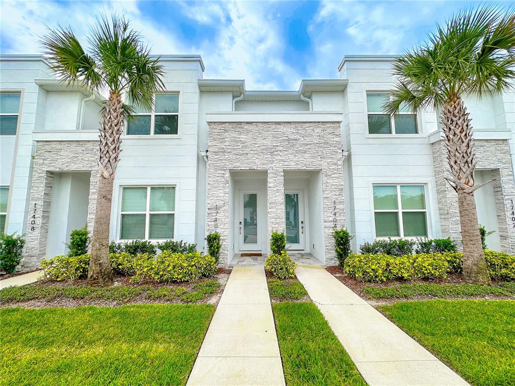 front view of a house with a yard and palm trees