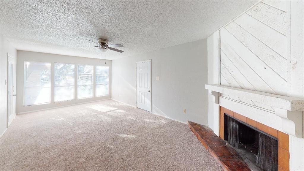 a view of an empty room with a fireplace and a window