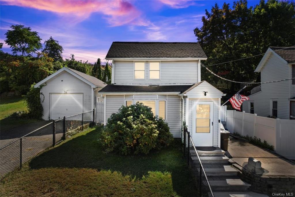 View of front of house with a garage, a lawn, and an outdoor structure