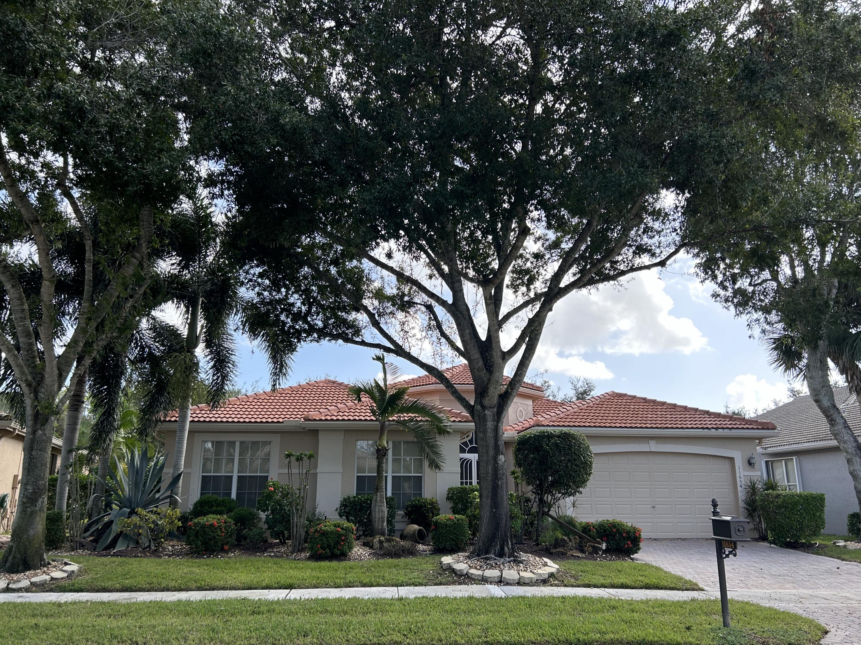 a front view of a house with a garden and trees