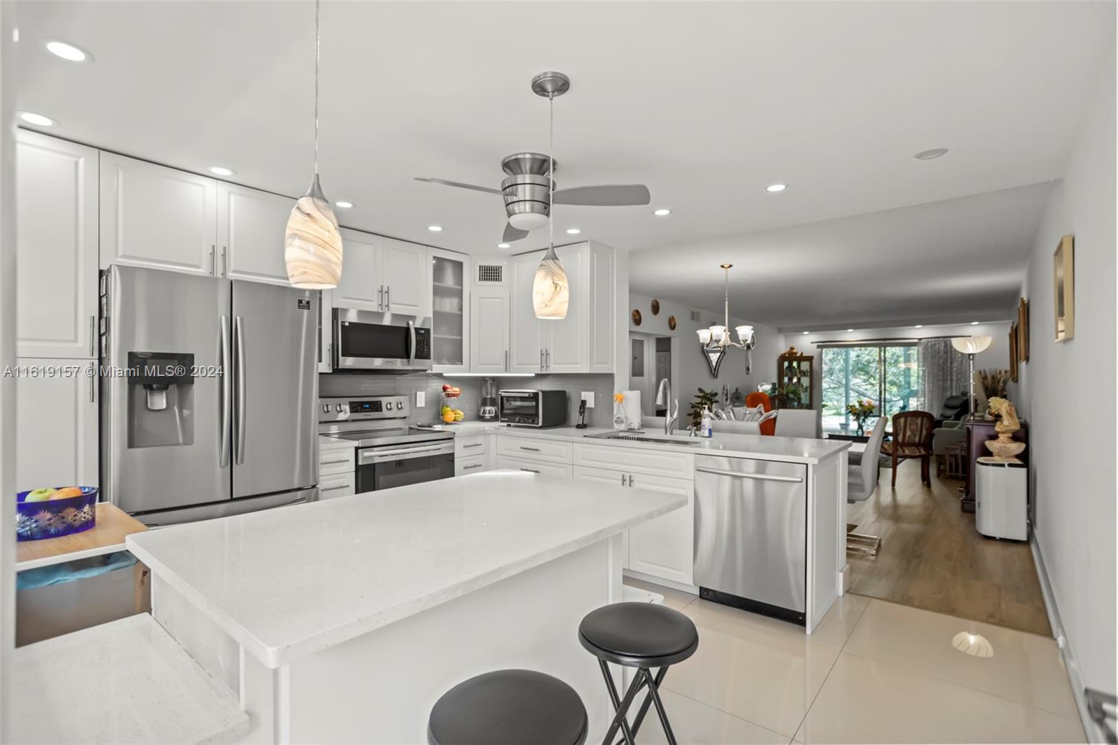 a kitchen with stainless steel appliances kitchen island granite countertop a refrigerator a sink dishwasher and white cabinets with wooden floor