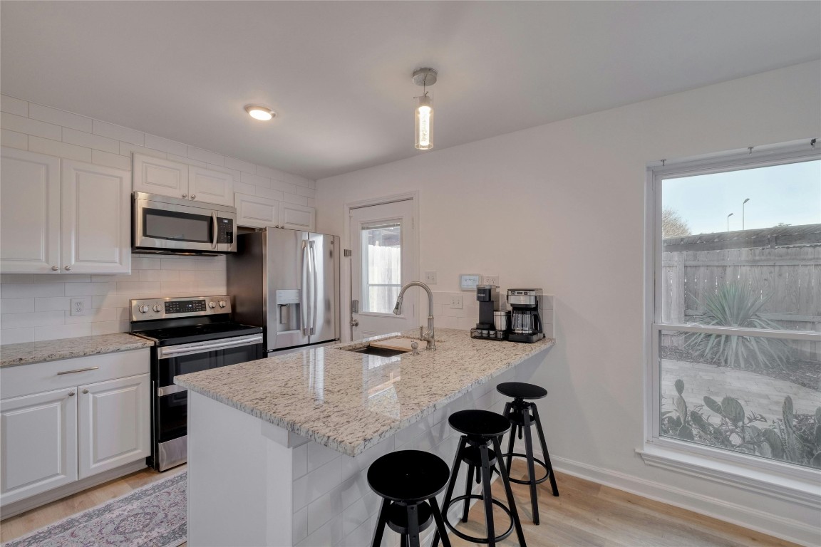 Granite countertop is deep enough for chairs to fit beneath. Kitchen sink has a cutting board and a drainage insert that rolls up for easy storage.