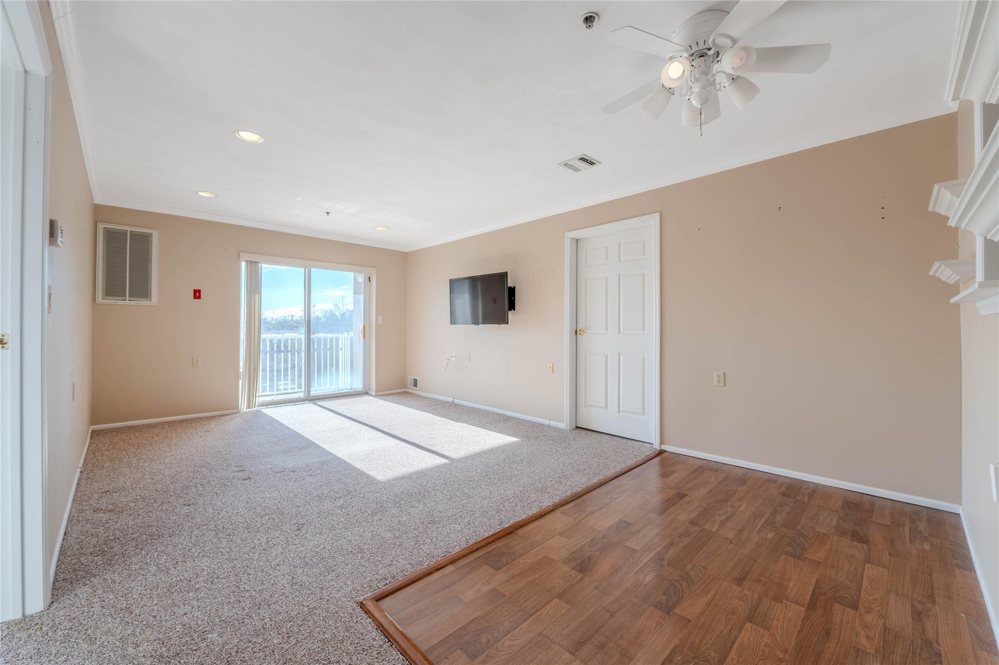 a view of empty room with wooden floor and fan