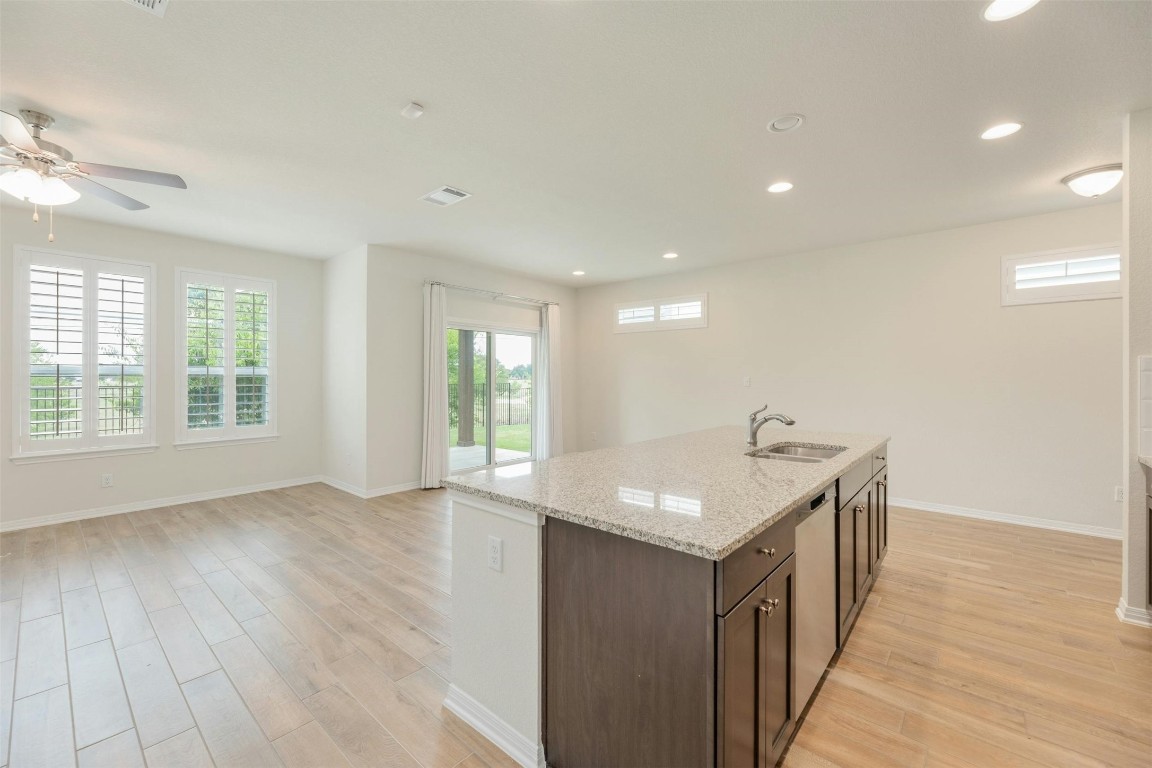 an open kitchen with a sink and dishwasher with wooden floor