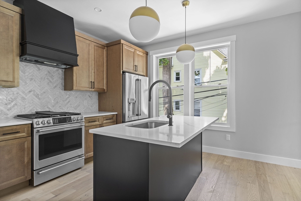 a kitchen with stainless steel appliances granite countertop a sink a stove and a wooden floors