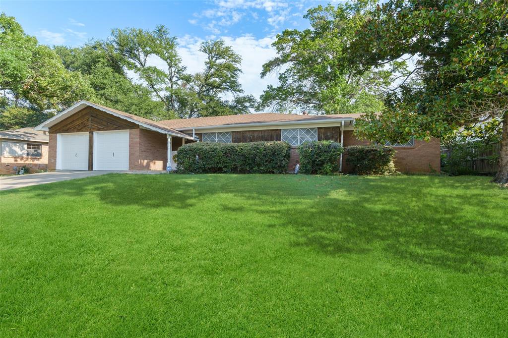 a view of a house with a yard and a large tree