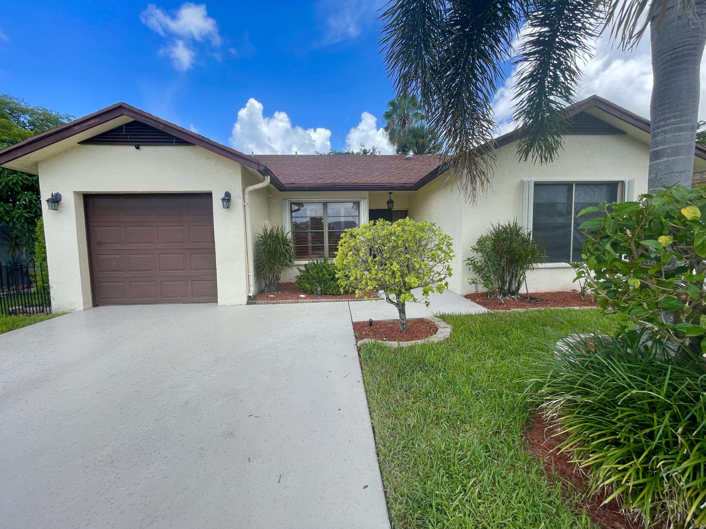 front view of a house with a yard and palm trees