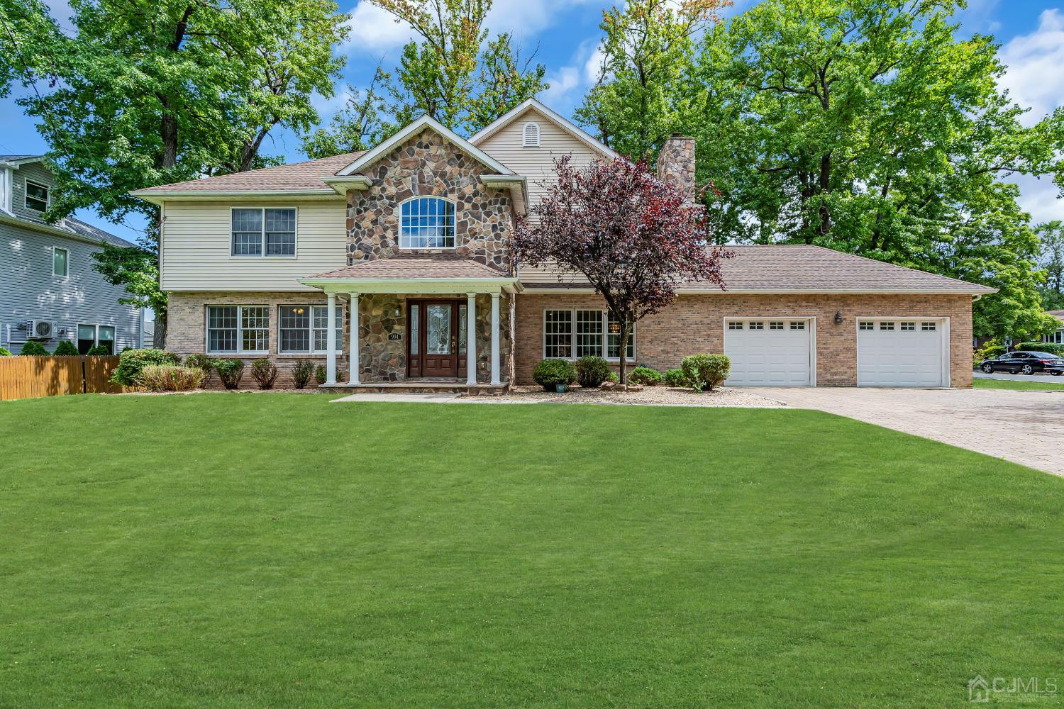 a front view of a house with a garden and trees