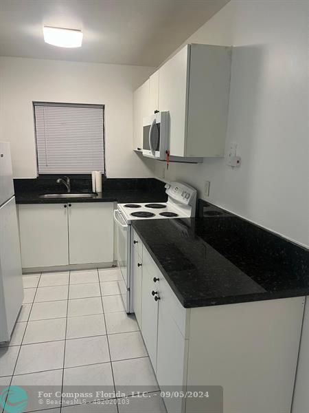 a kitchen with granite countertop a sink a stove and cabinets