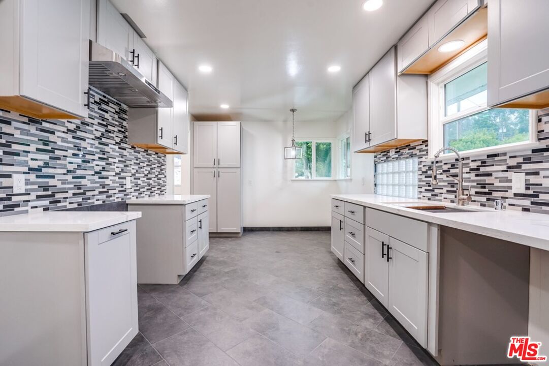 a kitchen with white cabinets and window