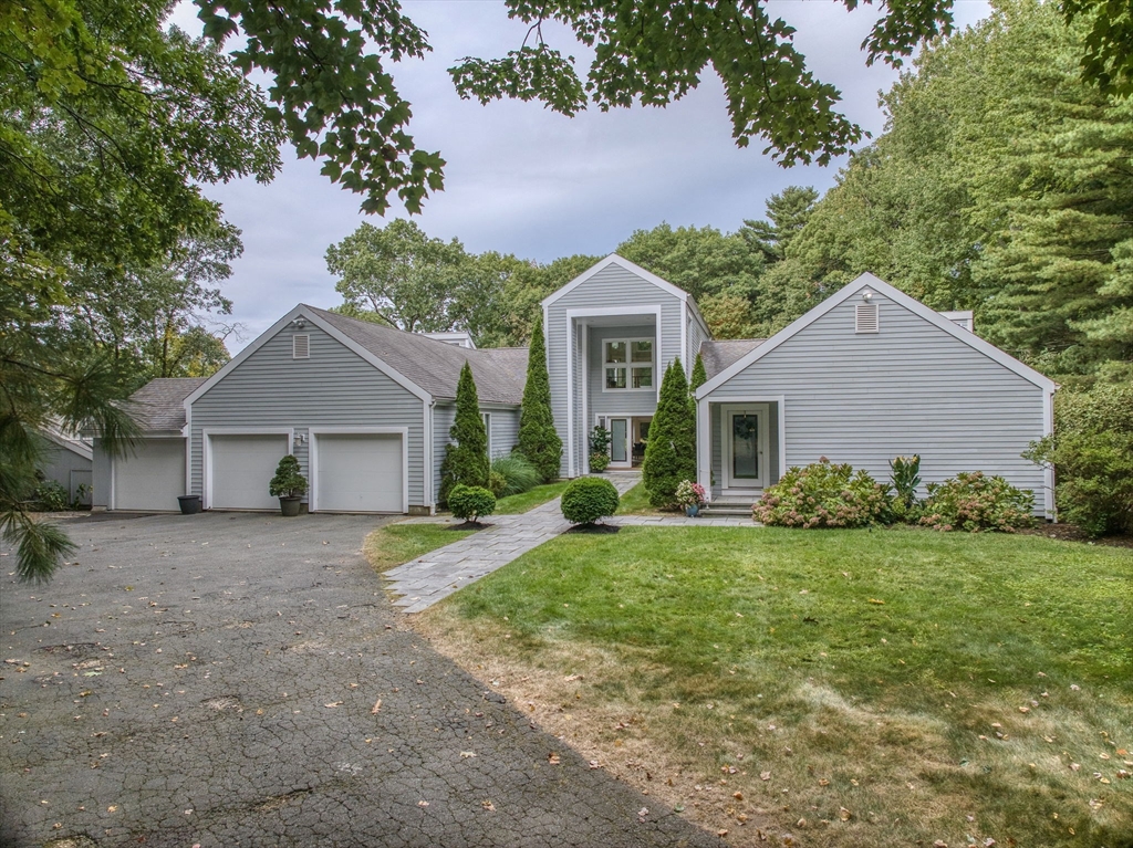 a front view of a house with a garden and trees