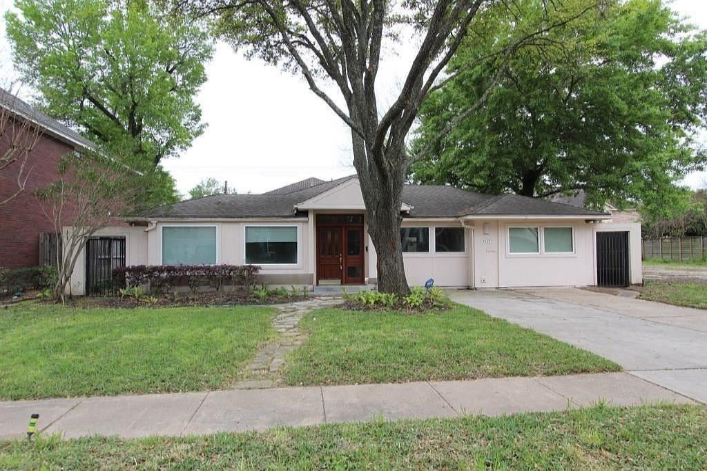 a front view of a house with a garden and trees