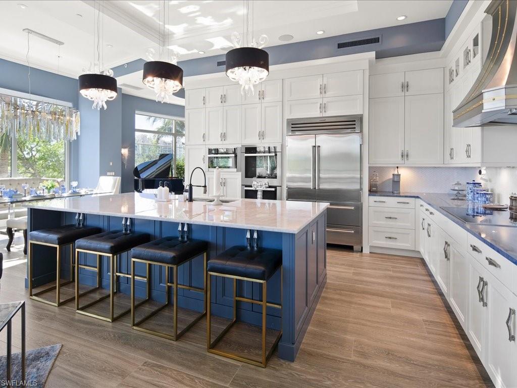 a kitchen with stainless steel appliances granite countertop a table chairs sink refrigerator and cabinets