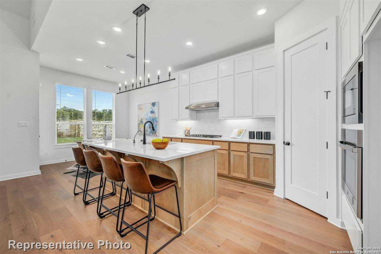 a kitchen with stainless steel appliances granite countertop a dining table chairs stove and white cabinets