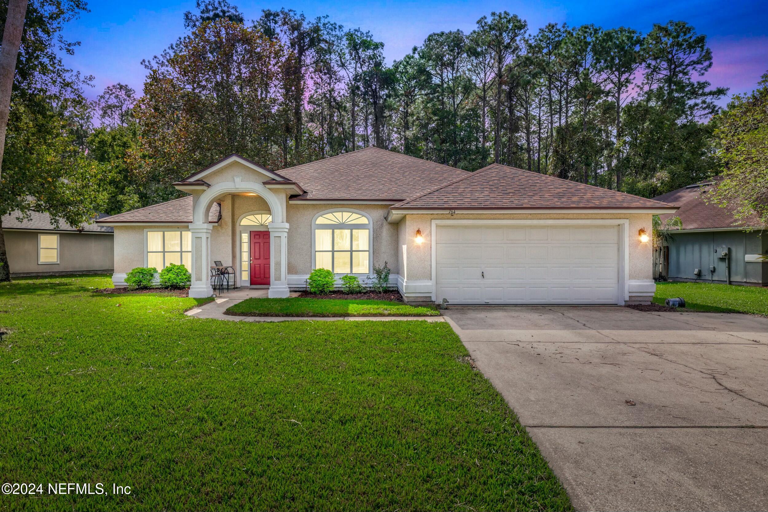 a front view of a house with a yard and trees