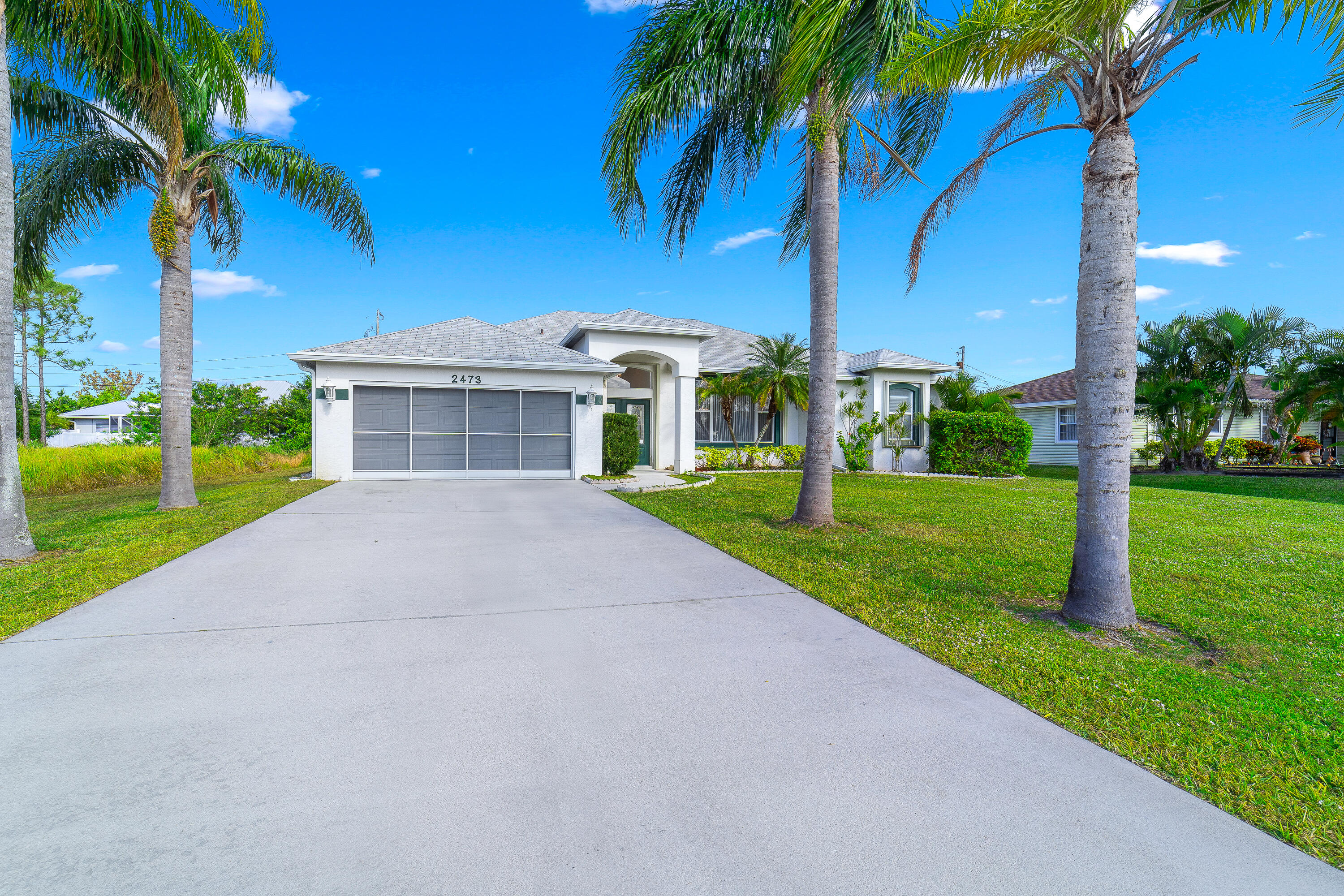 a view of a house with a yard and palm trees