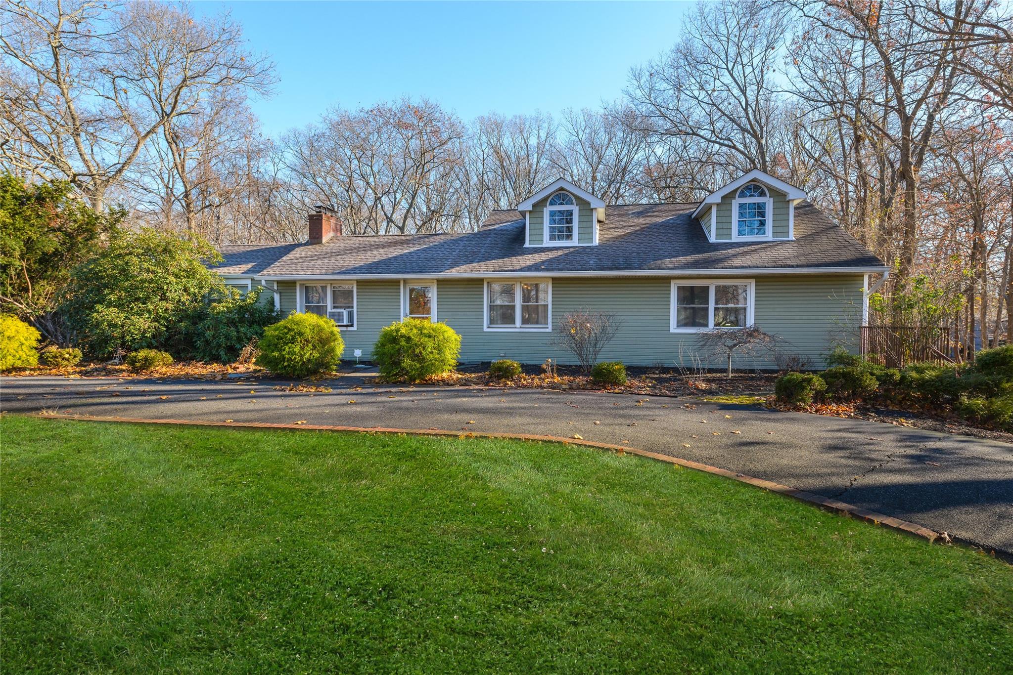 a front view of a house with a garden and trees