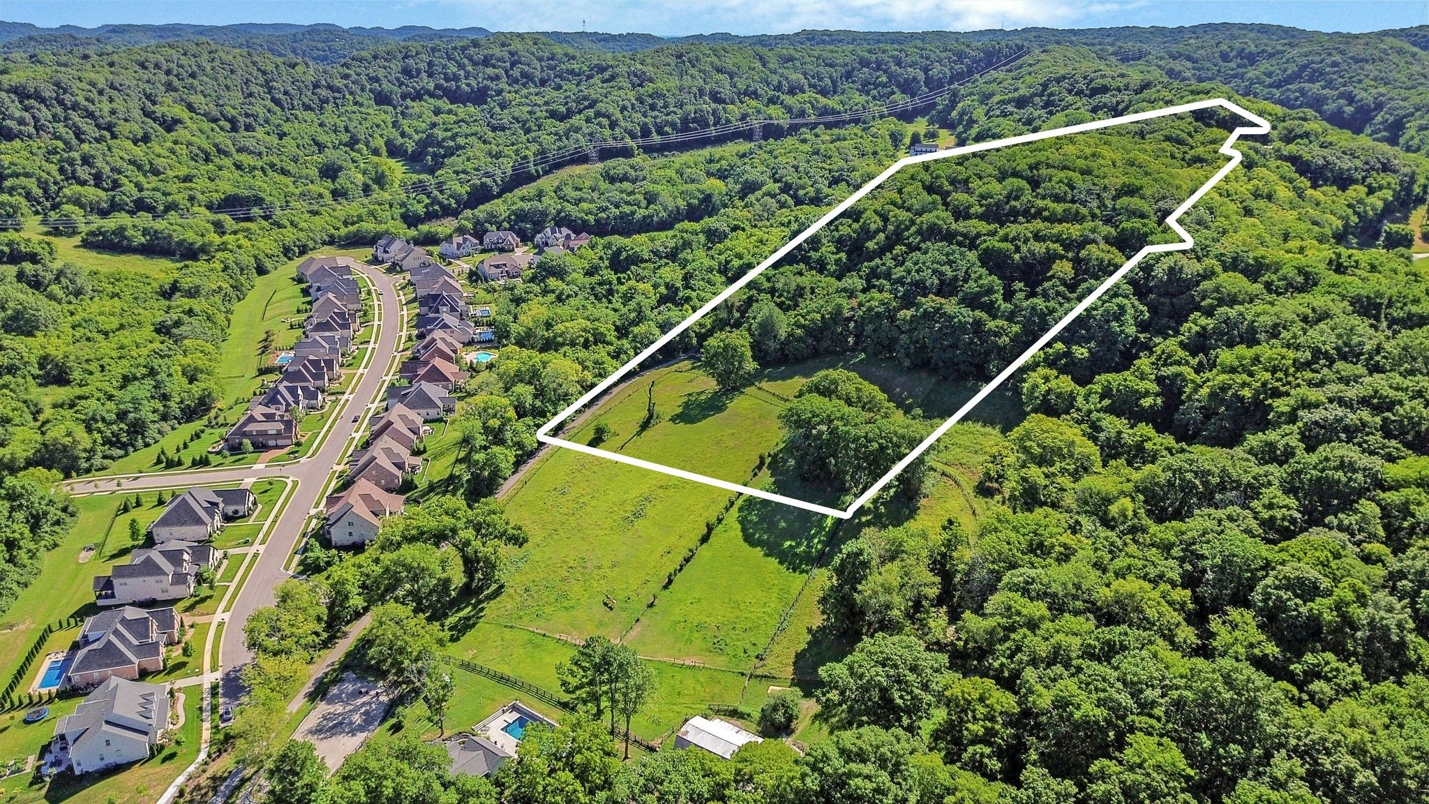 an aerial view of a residential houses with outdoor space and trees