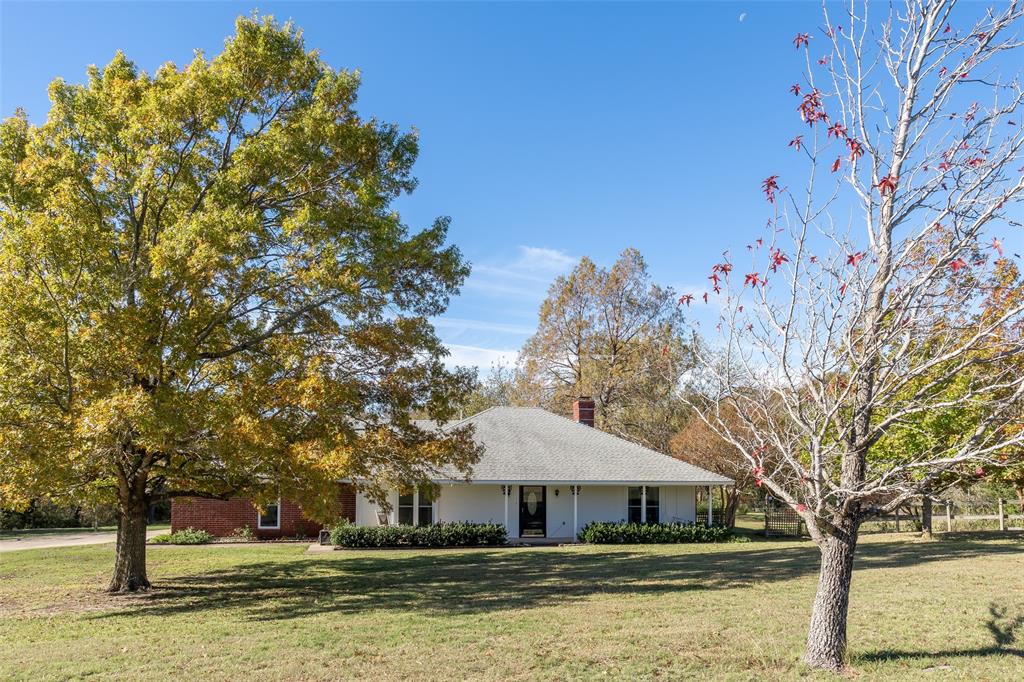 a front view of a house with a big yard and a large tree