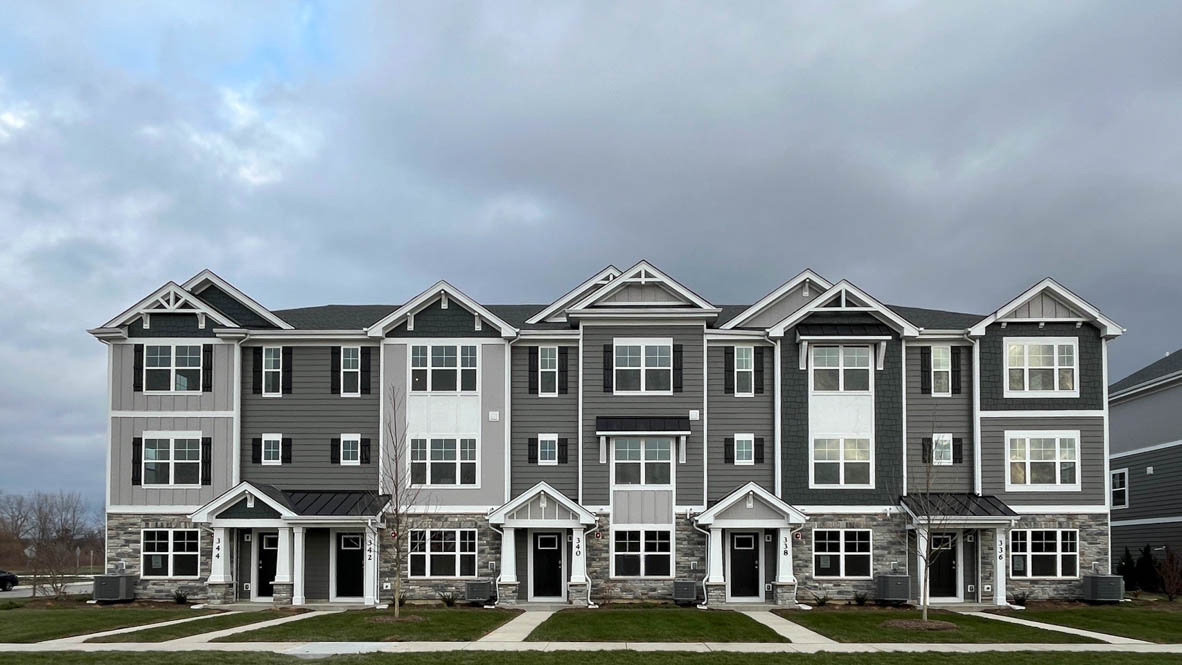 a front view of a residential apartment building with yard and parking space