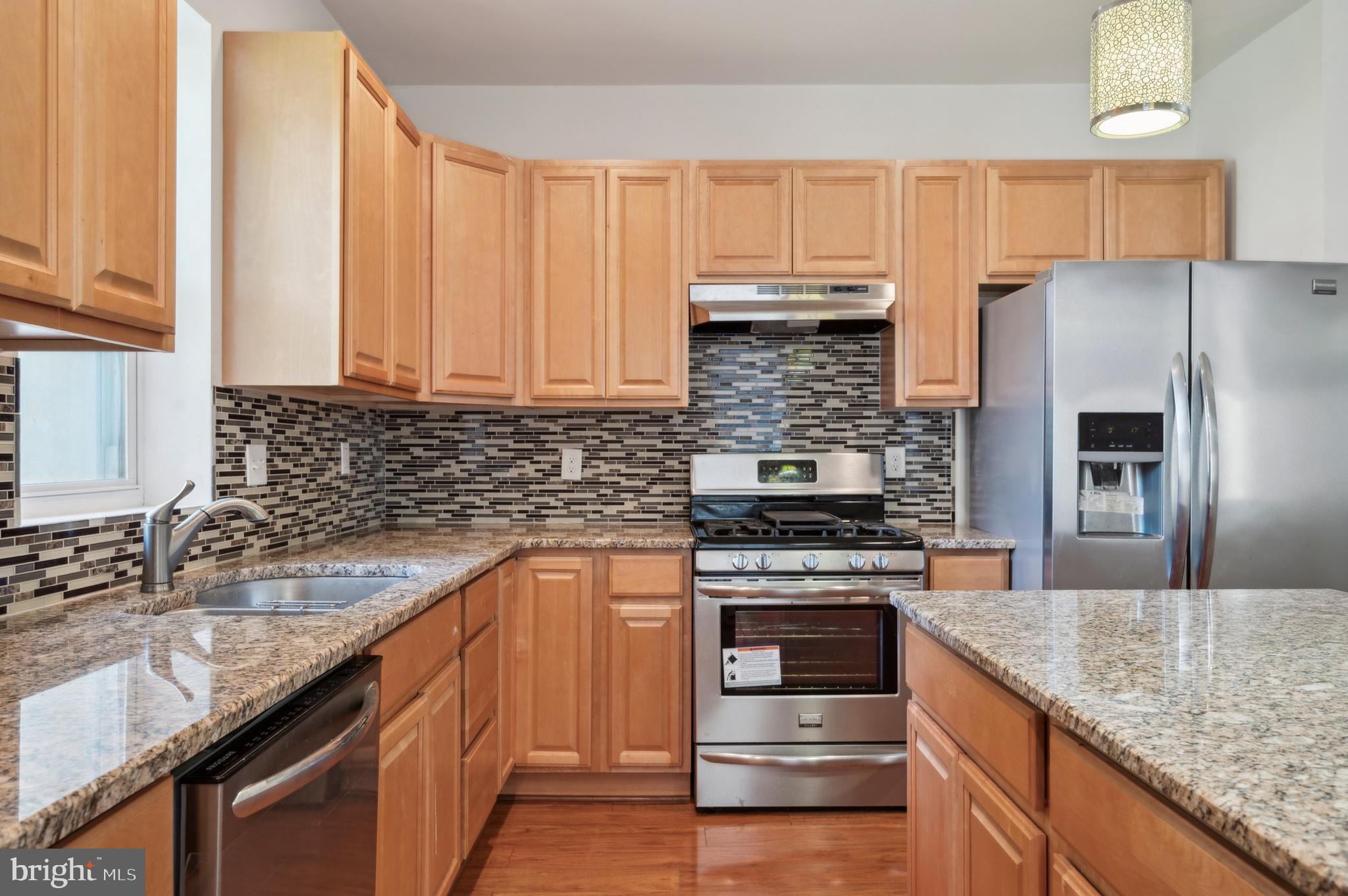 a kitchen with granite countertop a sink stainless steel appliances and cabinets