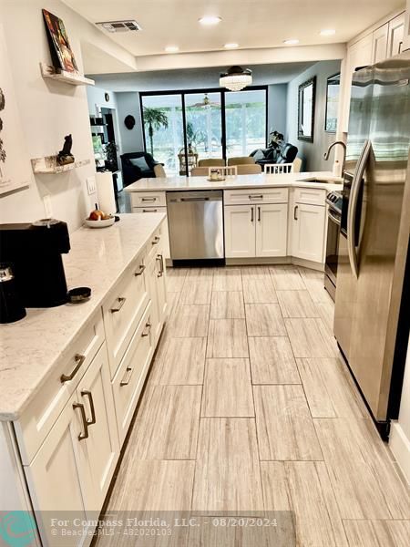 a large white kitchen with sink and refrigerator