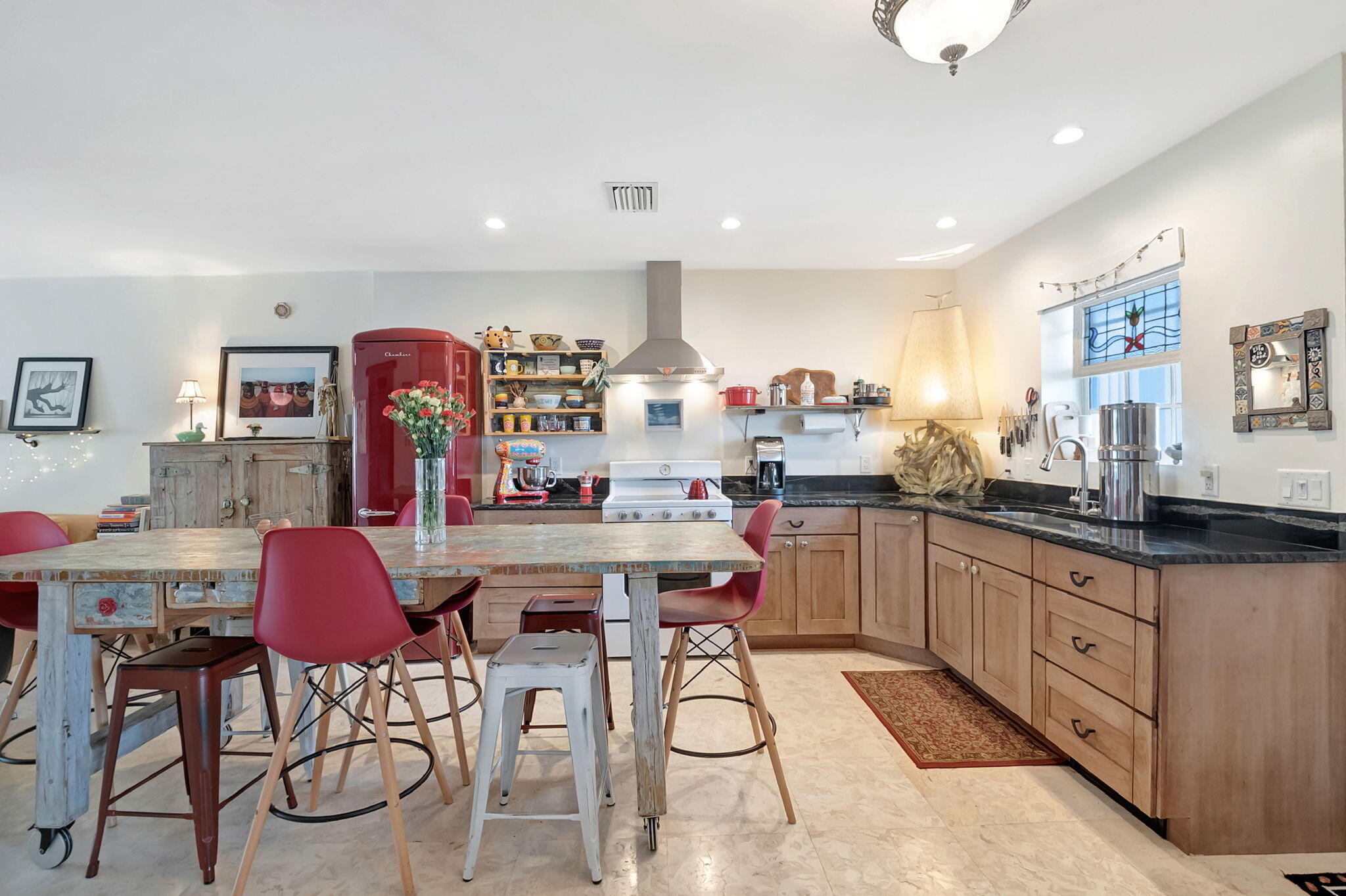 a kitchen with stainless steel appliances kitchen island granite countertop a table chairs sink and cabinets