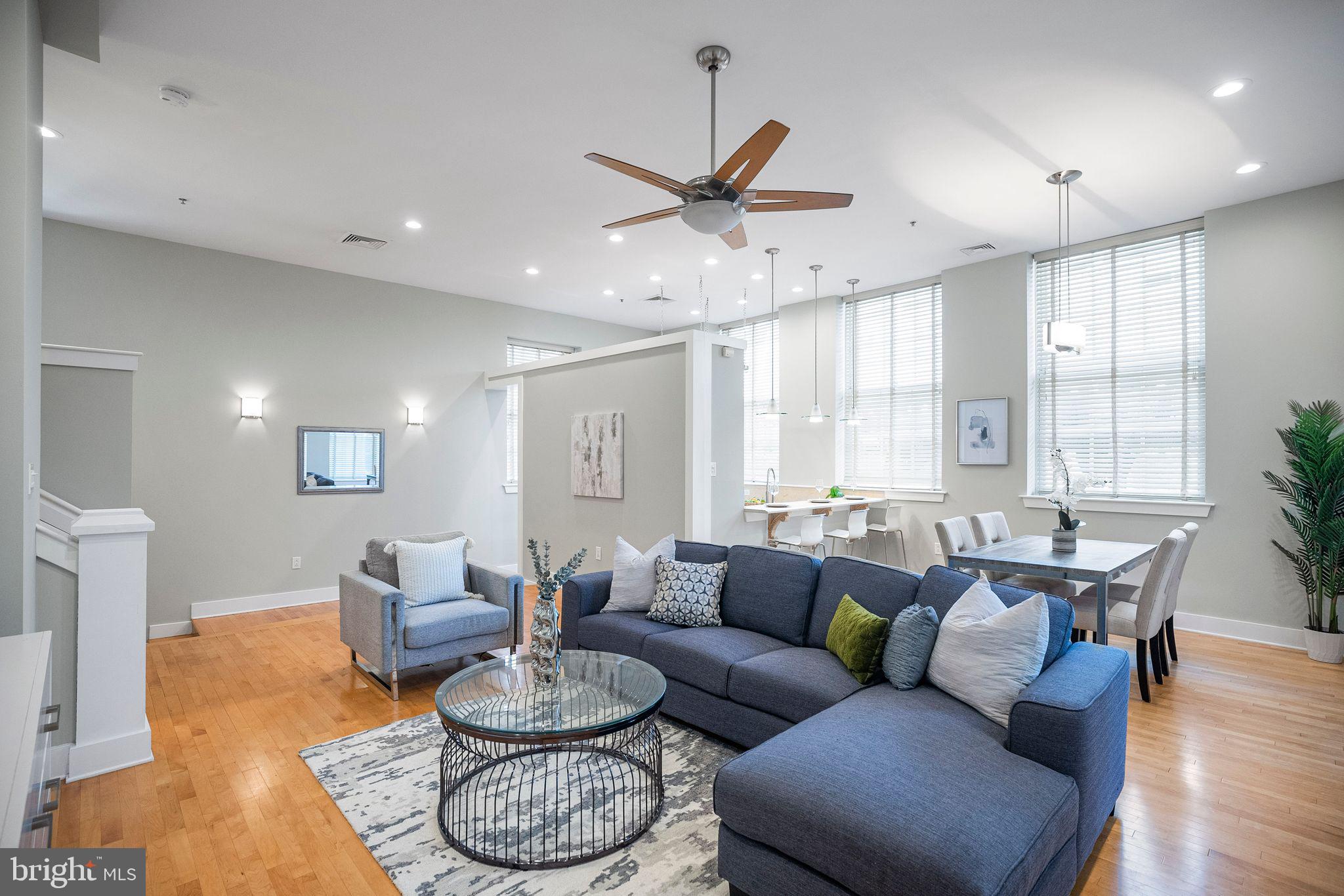 a living room with furniture a large window and wooden floor