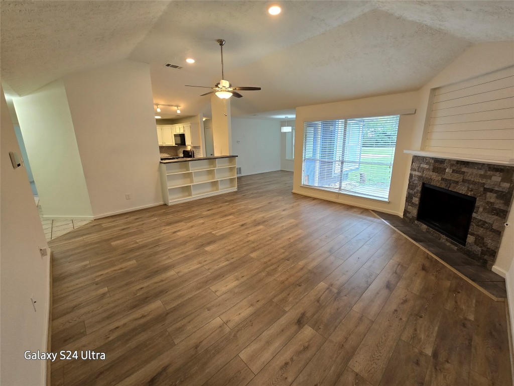 an empty room with wooden floor a fireplace and windows