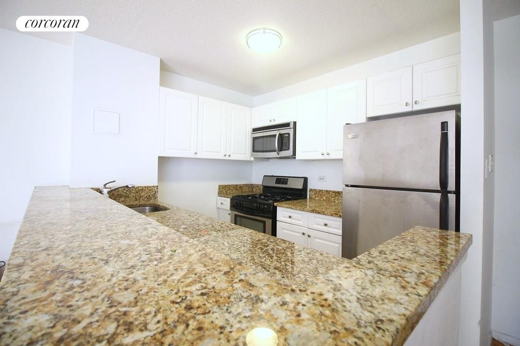 a kitchen with granite countertop a refrigerator and a stove top oven