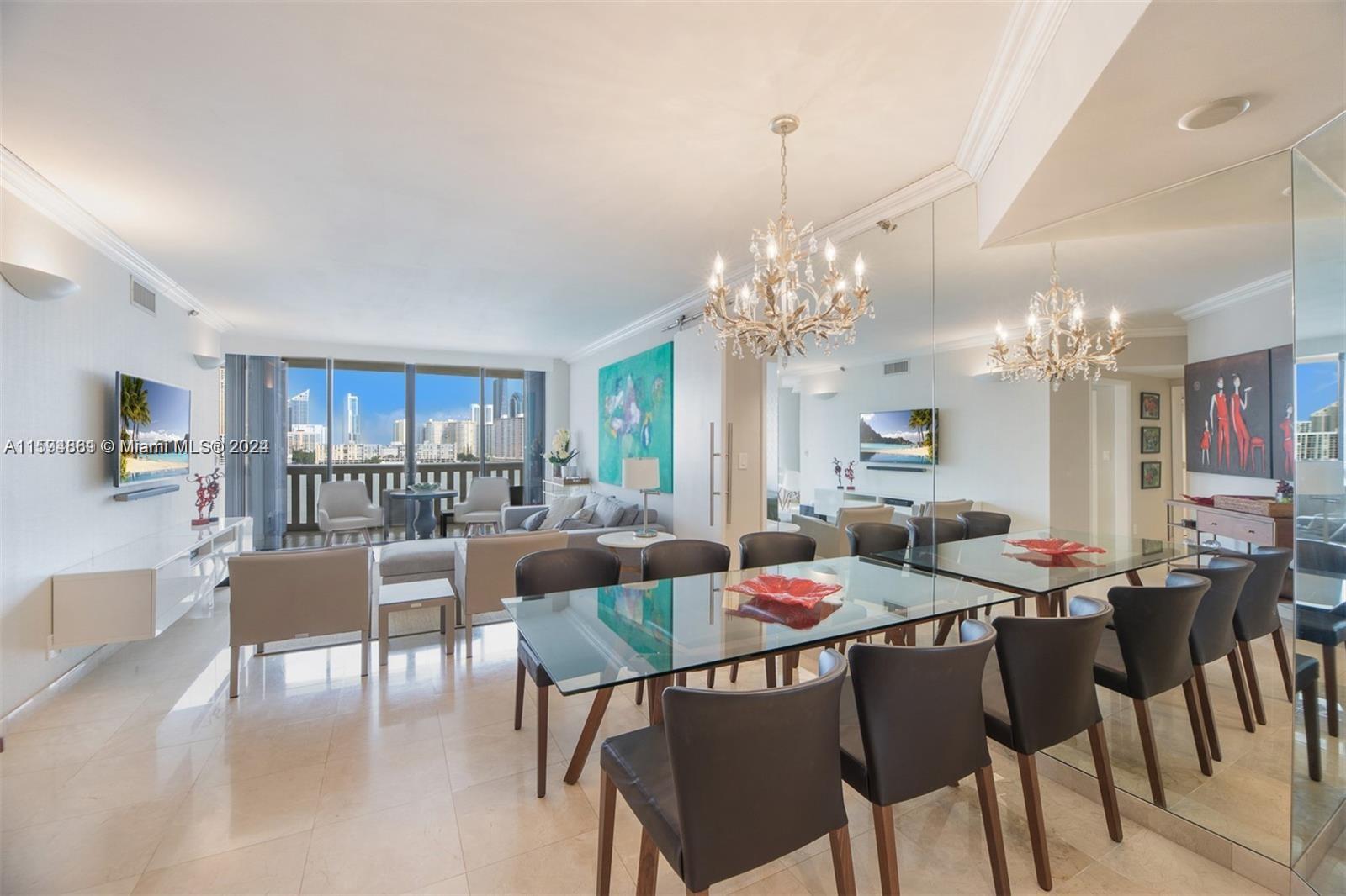 a view of a dining room and livingroom with furniture a rug a painting and a chandelier