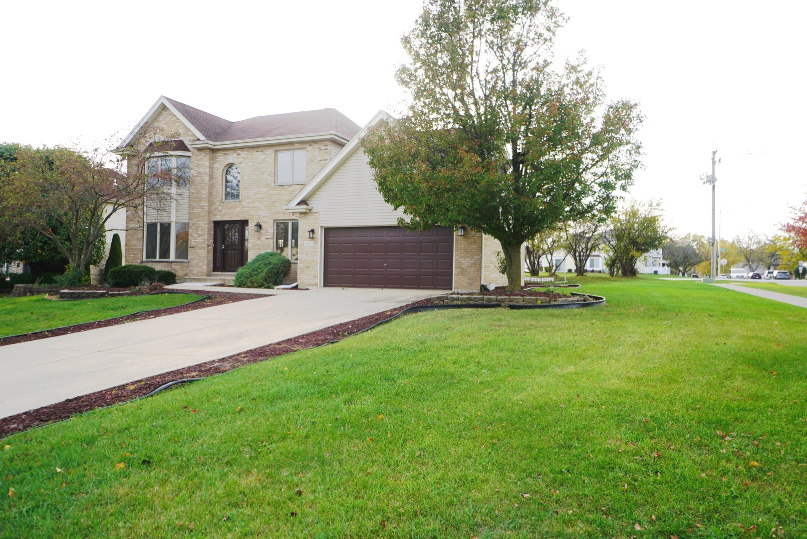 a view of house with a big yard and large trees