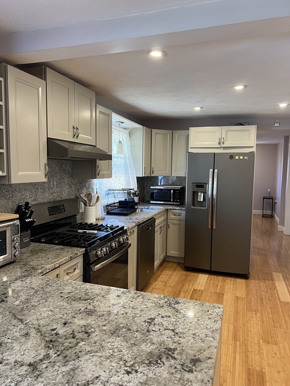 a kitchen with granite countertop a refrigerator and a stove top oven