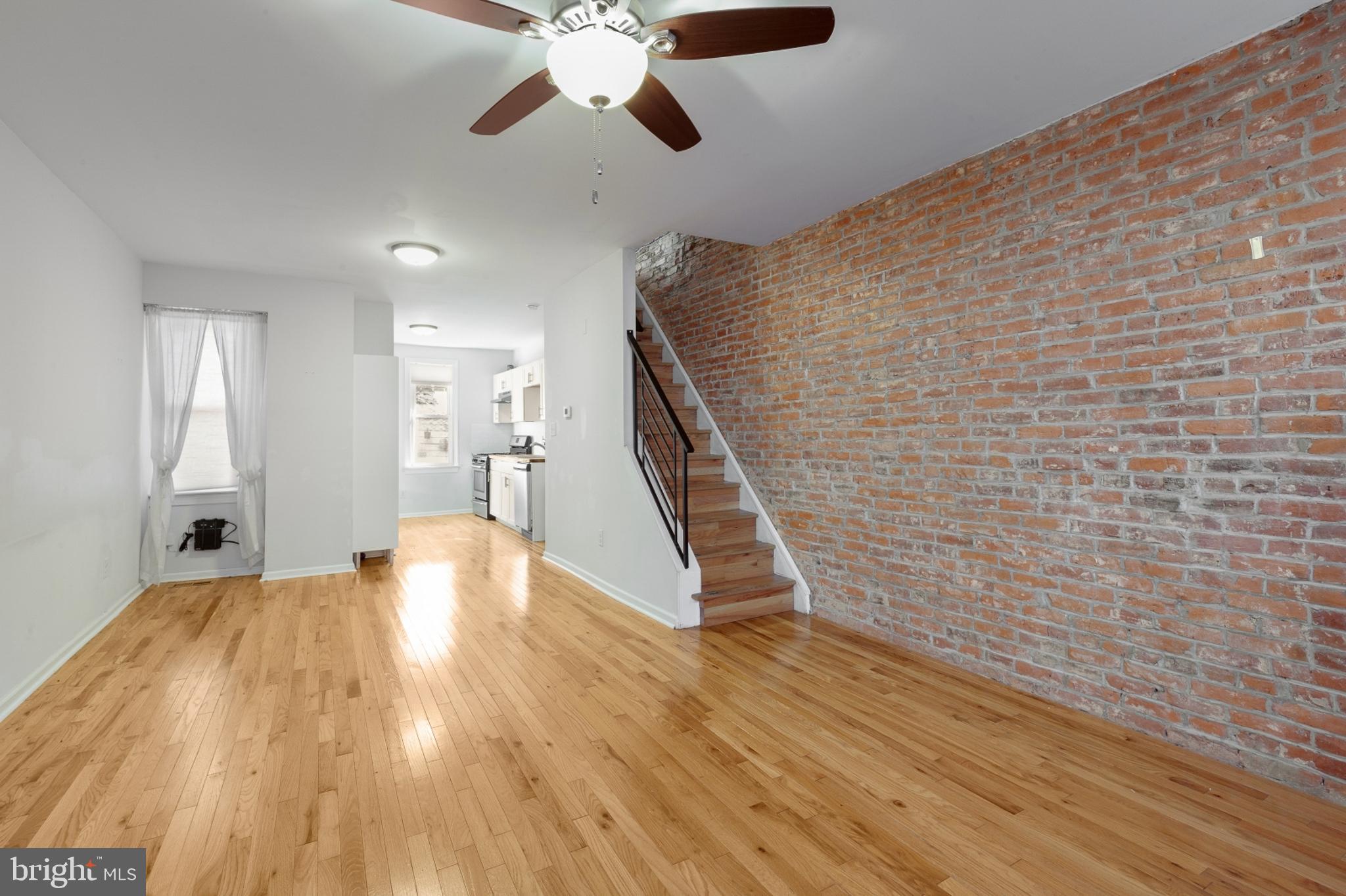 a view of an empty room with wooden floor and a chandelier