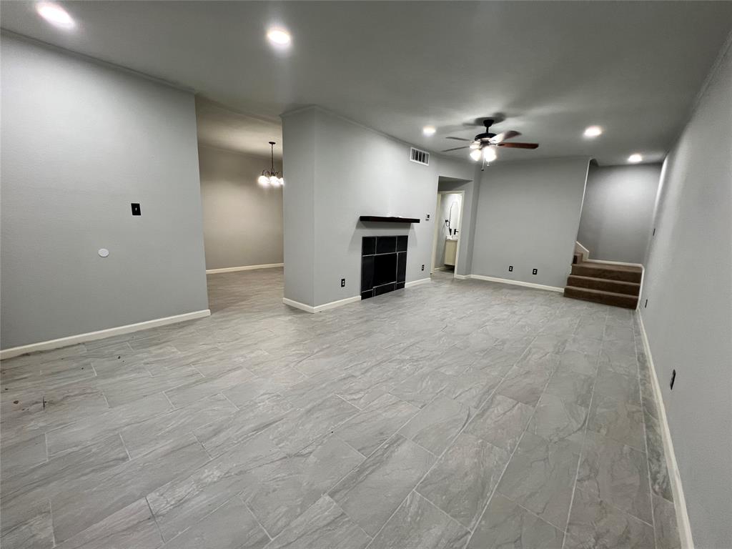 an empty room with fireplace and a chandelier fan