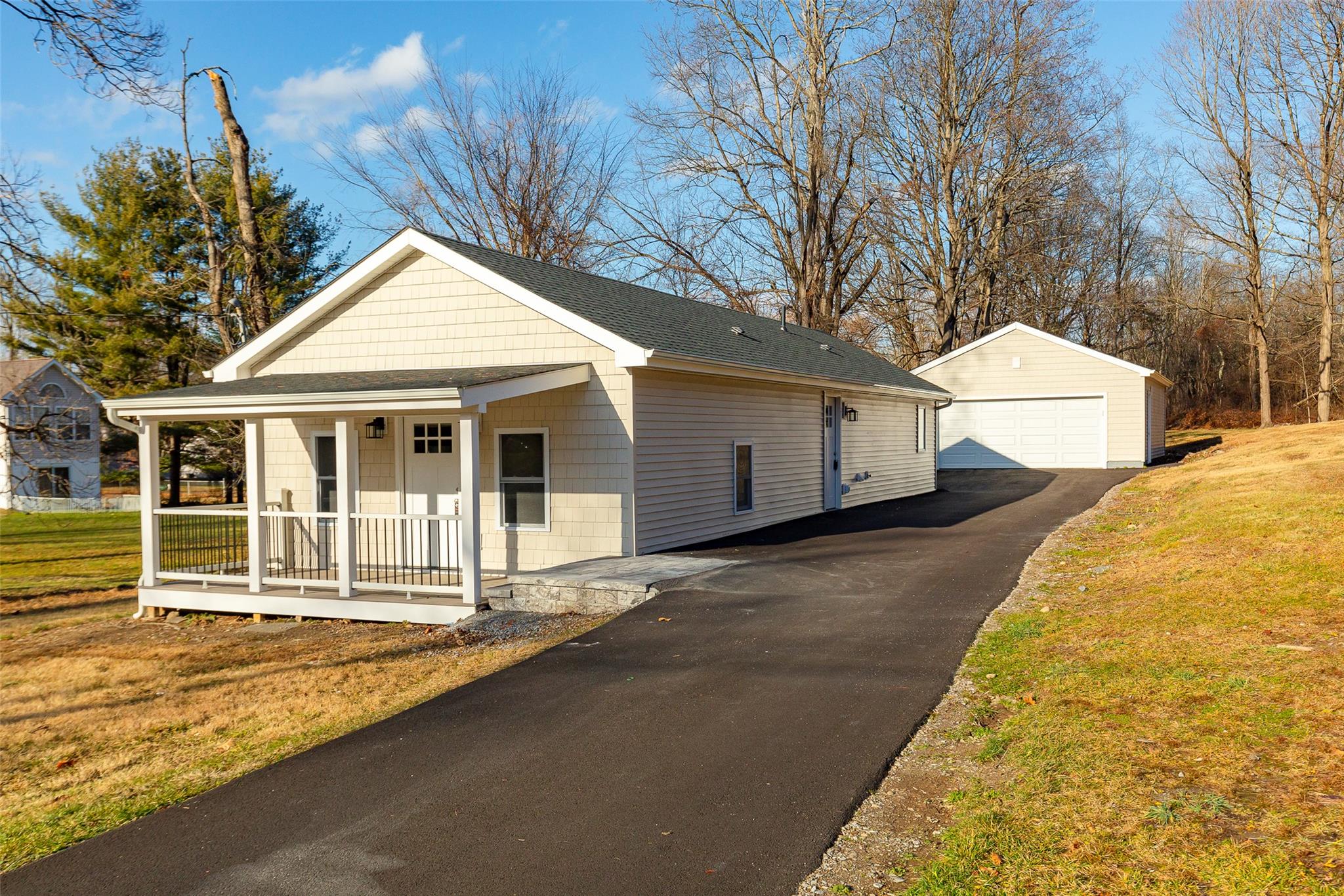 View of front of house with a porch, a garage, an outdoor structure, and a front yard