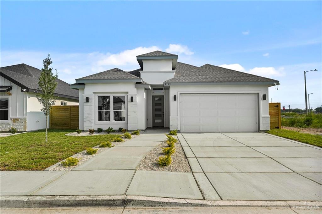 View of front facade featuring a garage and a front lawn