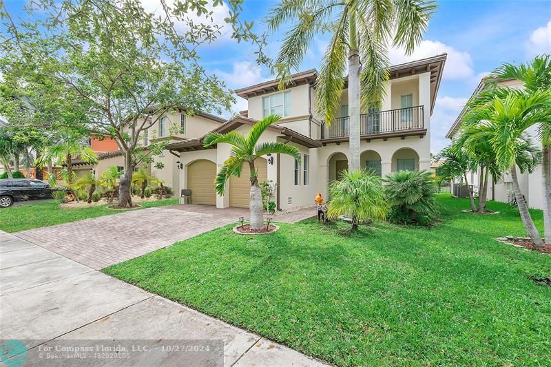 front view of house with a yard and palm trees