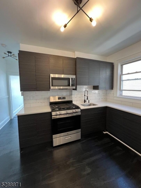 a kitchen with stainless steel appliances a sink cabinets and wooden floor