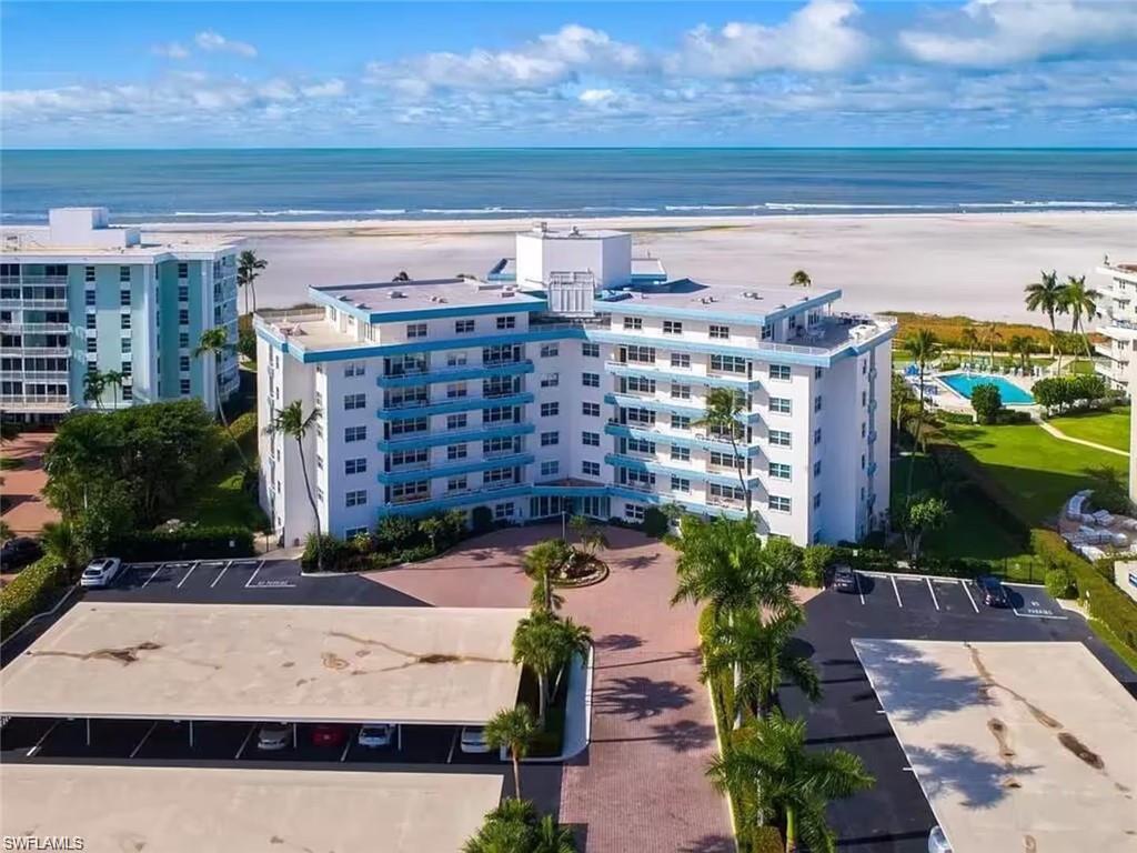 Birds eye view of property with a water view and a view of the beach