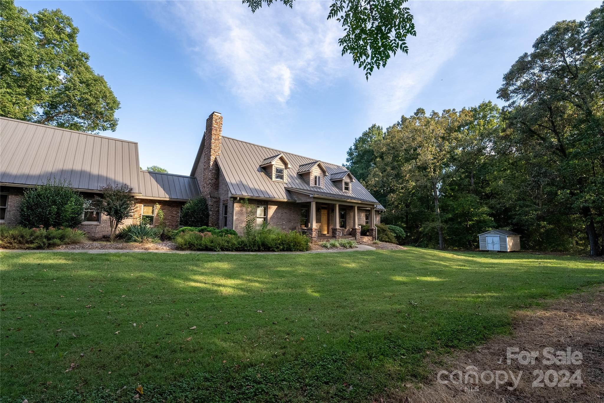 a view of a big house with a big yard and large trees