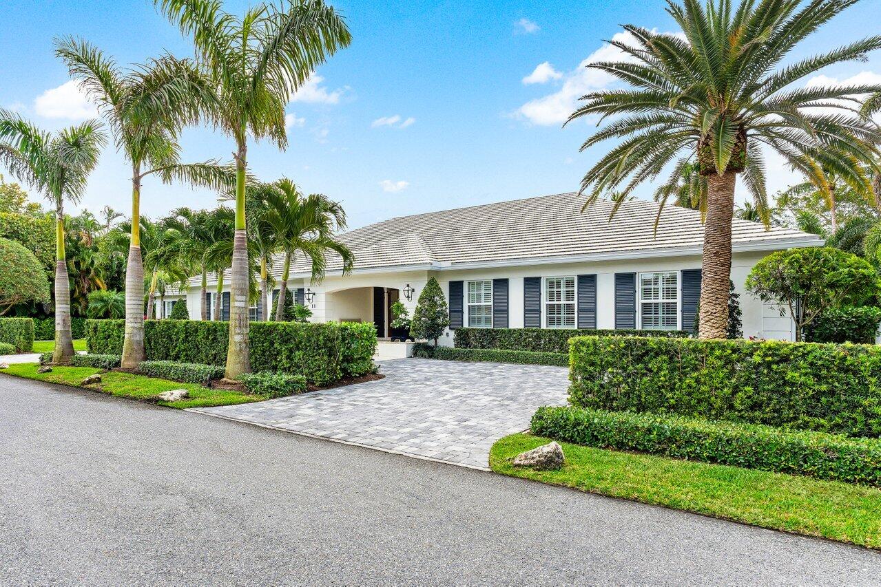 a front view of house with small garden and palm trees