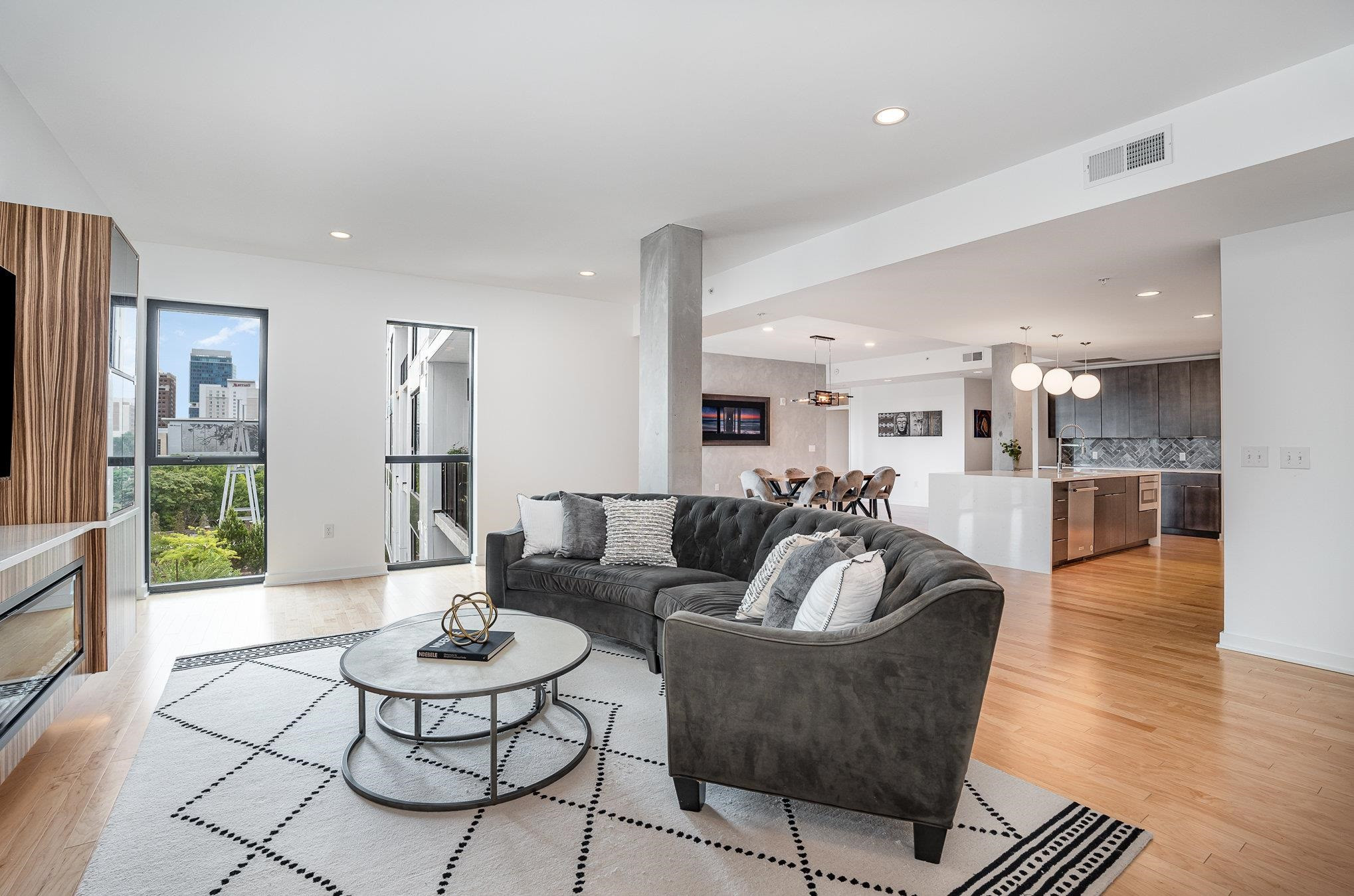 a living room with furniture kitchen view and a wooden floor