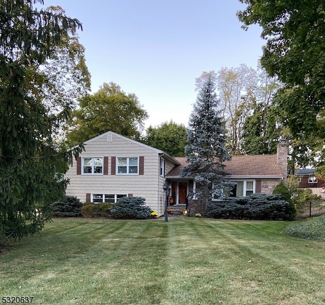 a front view of a house with a garden and trees