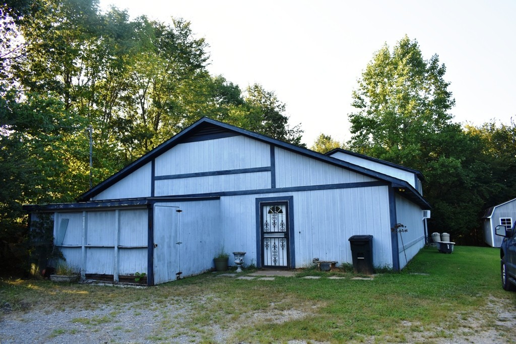 a view of a small house with a big yard and large tree