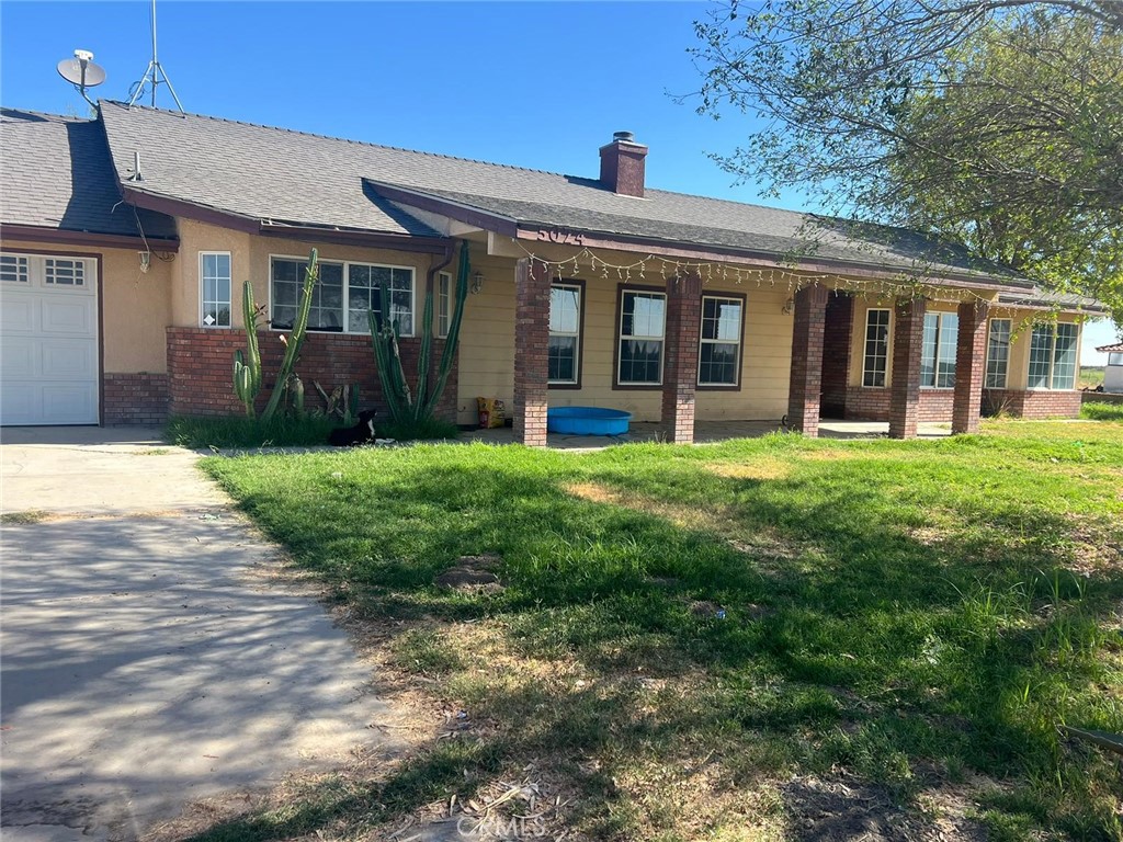 a view of a brick house with a big yard and large trees