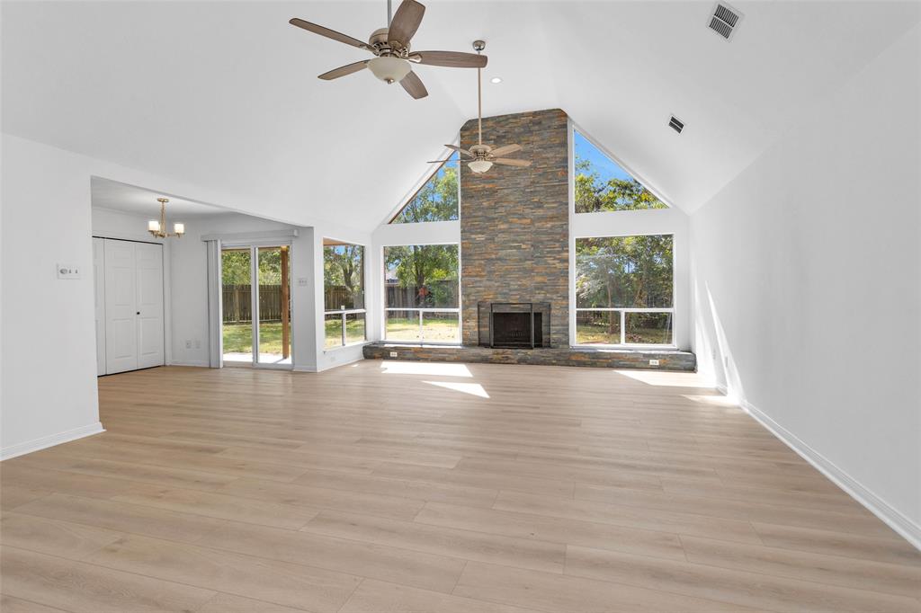 Welcome to 2306 Woven Wood Lane in The Grove with a sun filled Family Room showcasing a stunning floor-to-ceiling stone gas fireplace, complemented by soaring vaulted ceilings & wall of windows.