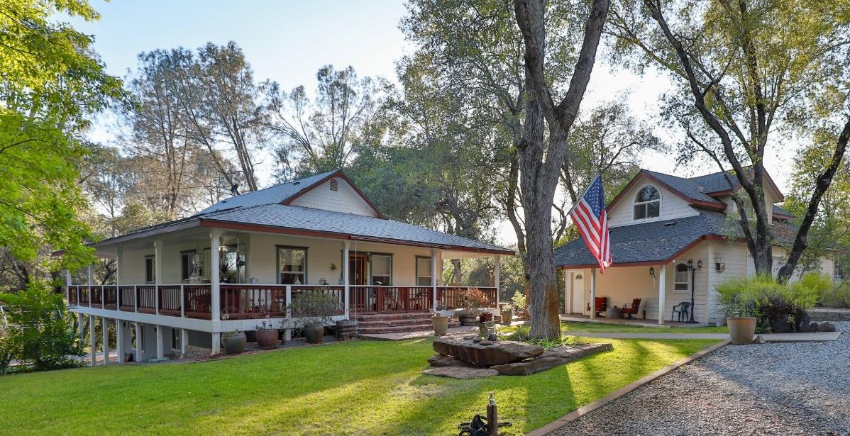 a view of a house with a yard and large trees