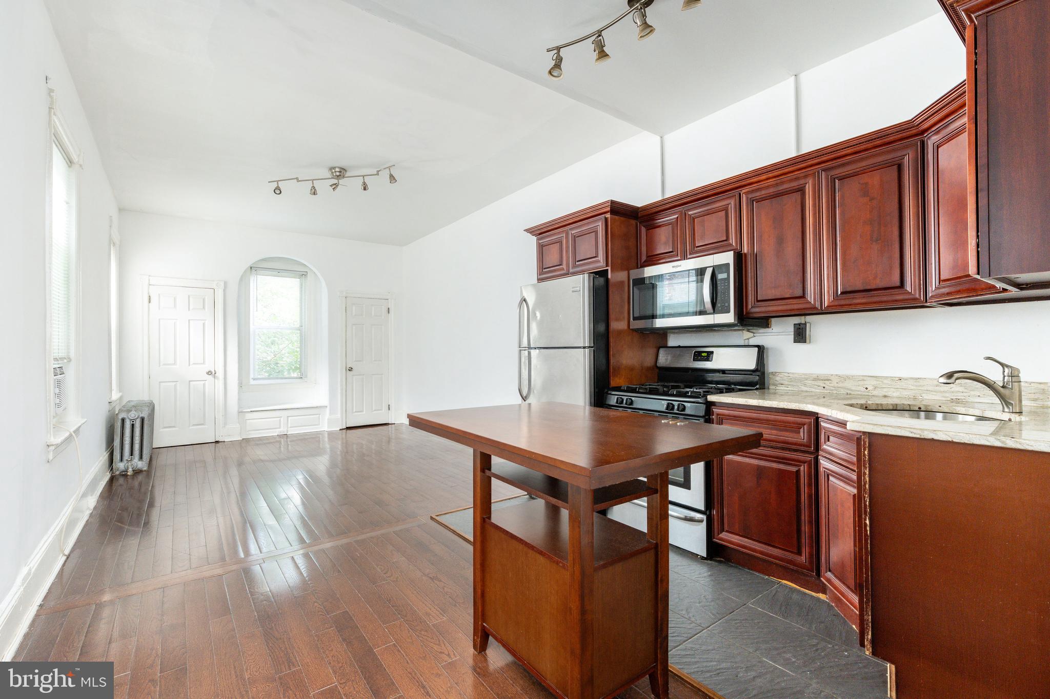 a kitchen with stainless steel appliances granite countertop a stove top oven a sink dishwasher and a microwave with wooden floor